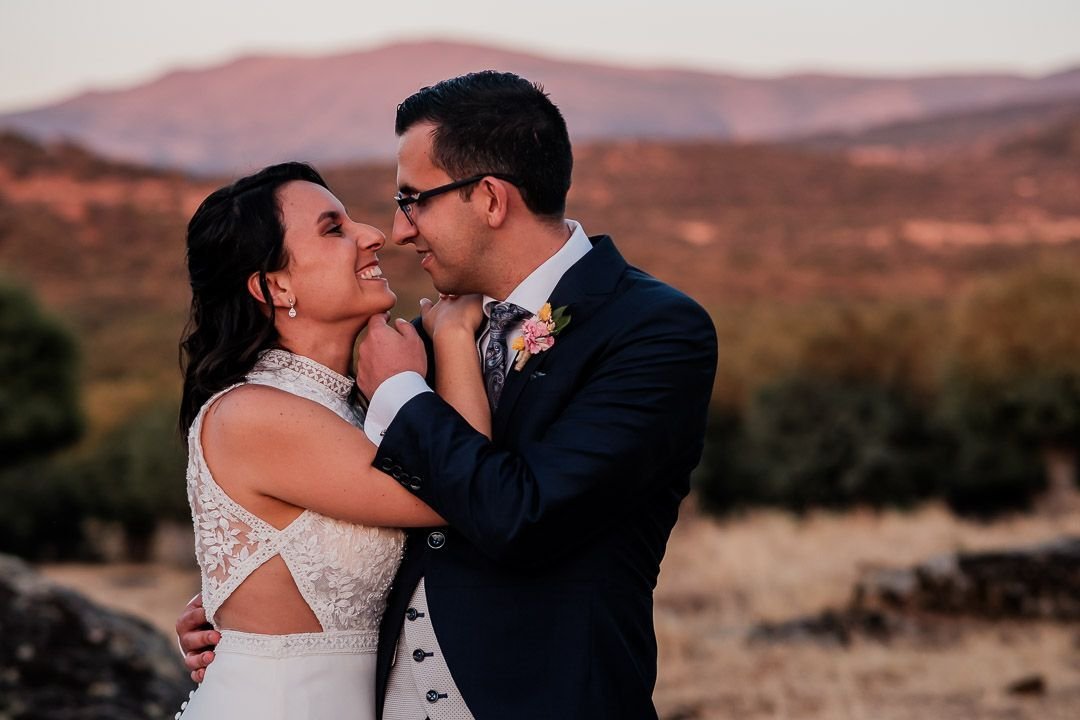 Noelia y Carlos sonríen abrazados ante las montañas al atardecer.