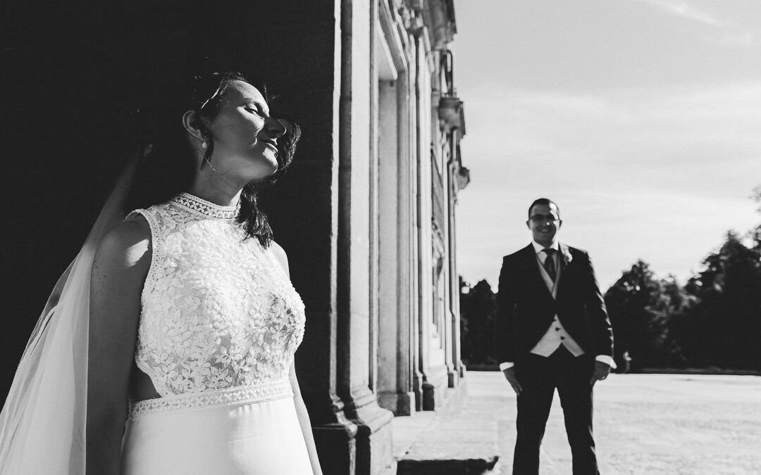 Retrato en blanco y negro de Noelia junto a la fachada, con Carlos al fondo.