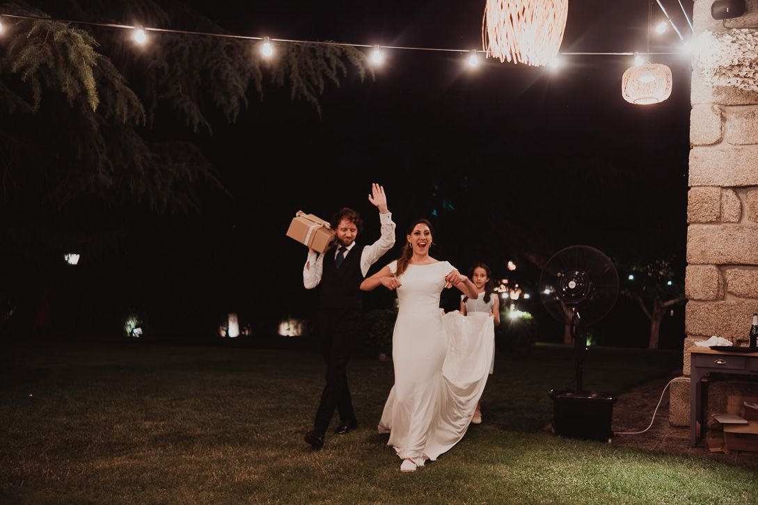 Los novios llegan con regalos a la celebración nocturna bajo las guirnaldas.