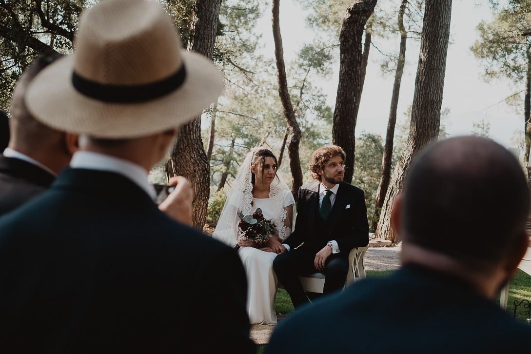 La pareja escucha la ceremonia al aire libre, vista entre los invitados.