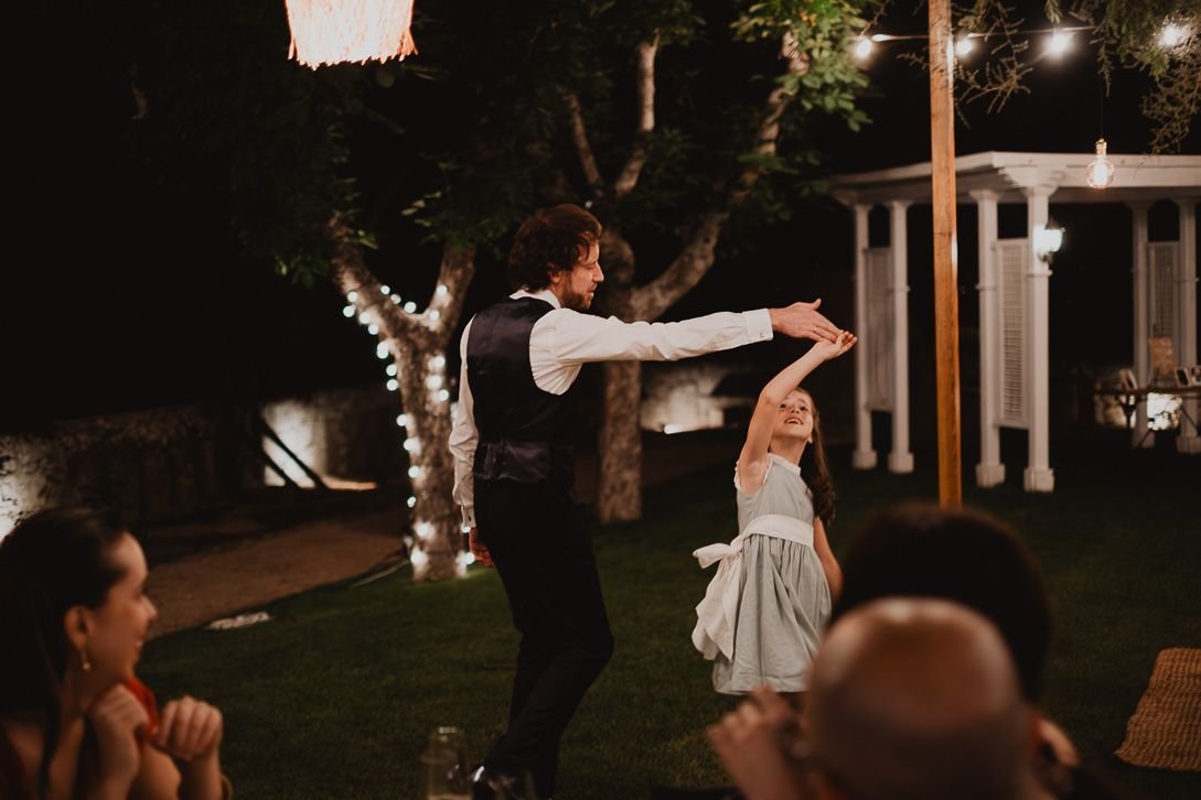 David baila con una niña bajo las luces del jardín.