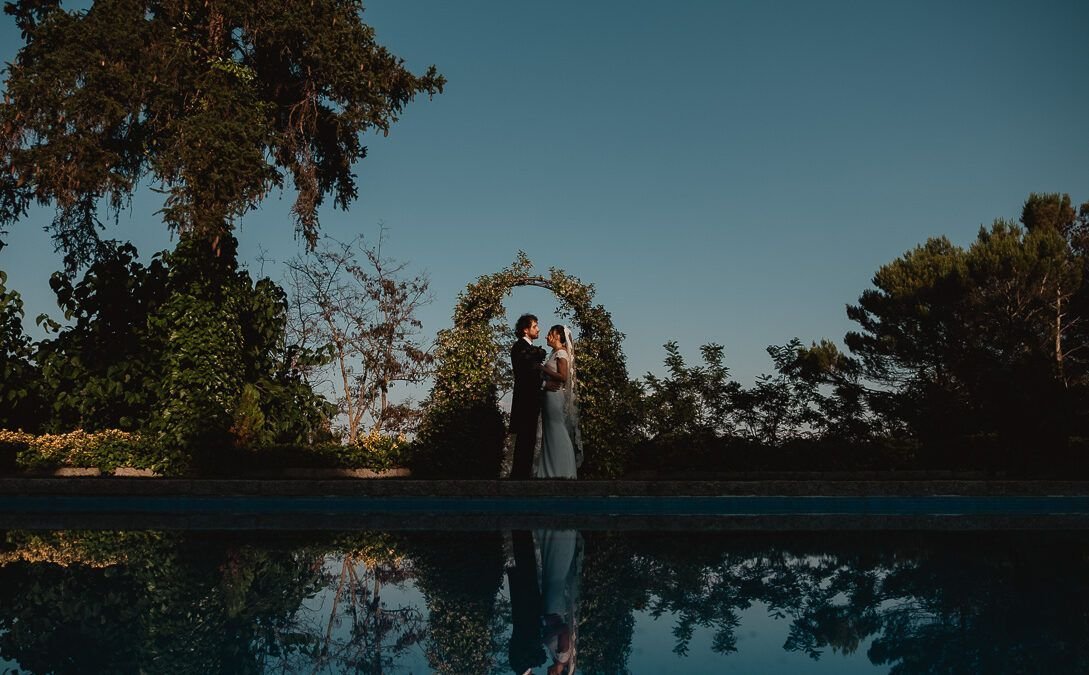 Natalia y David bajo un arco vegetal, reflejados en la piscina de la finca.
