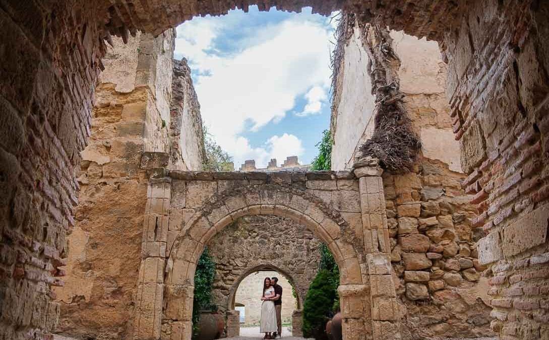 Lara y Javi bajo una sucesión de arcos de piedra en su preboda en Pedraza.