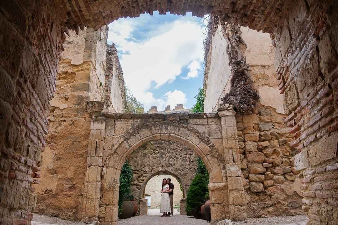 Lara y Javi bajo una sucesión de arcos de piedra en su preboda en Pedraza.