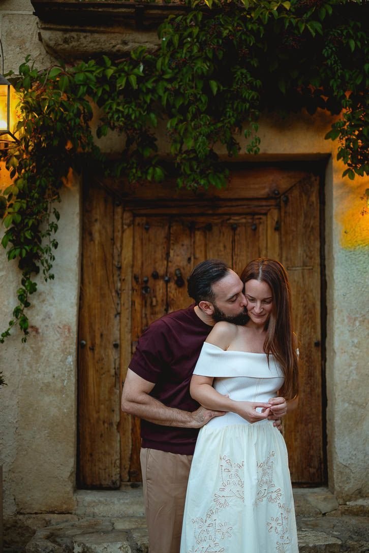 Javi besa la mejilla de Lara ante una puerta de madera durante su preboda en Pedraza.