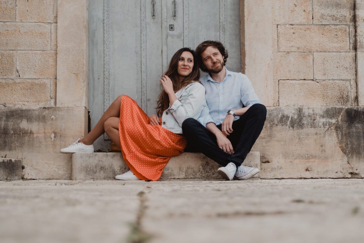 Natalia y David sentados ante una puerta en su preboda en el Pontón de la Oliva.