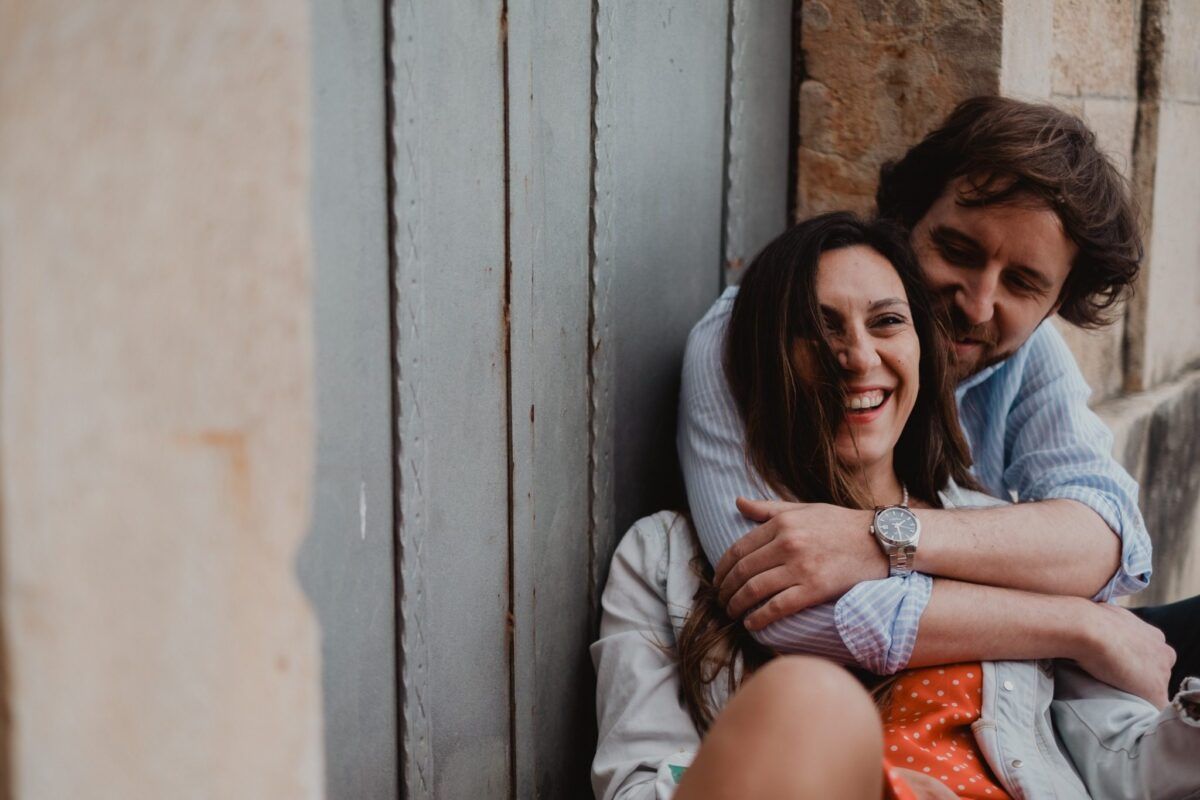 Natalia ríe mientras David la abraza por detrás junto a una puerta.