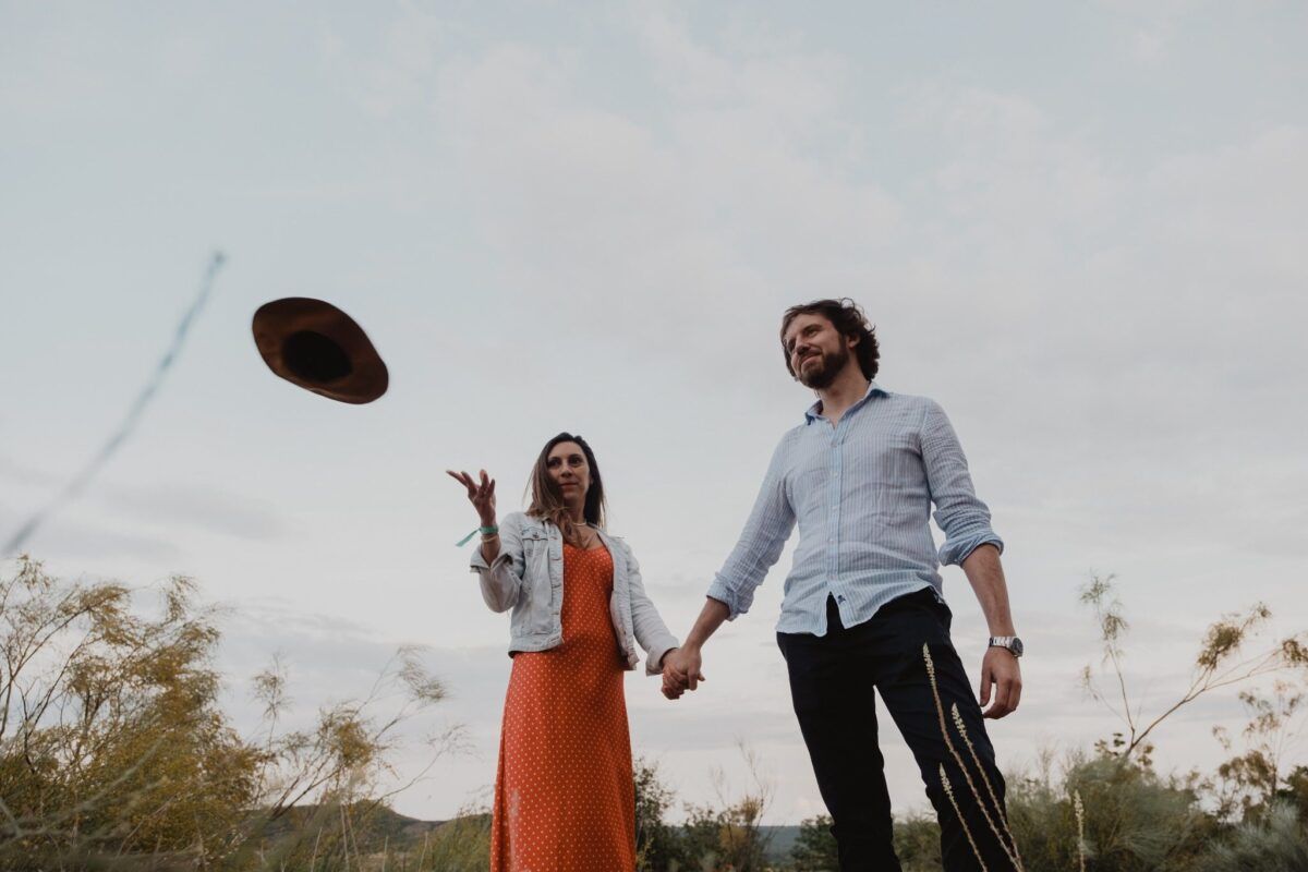 Natalia lanza su sombrero al aire mientras sostiene la mano de David en el campo.