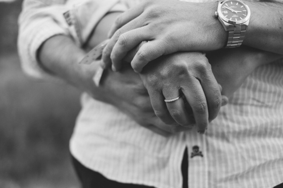 Detalle en blanco y negro de las manos de Natalia y David, con el anillo y el reloj.