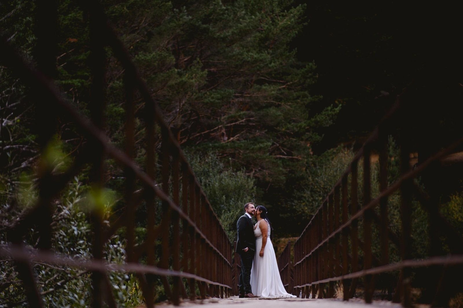 Paola y José sobre un puente de madera rodeado de pinos